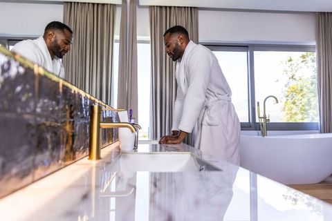 African american man leaning on glossy marble vanity in modern luxury bathroom