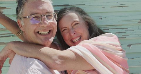 Smiling Senior Couple Embracing Outdoors Against Green Wall
