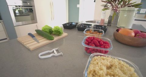 Modern kitchen meal-prep island with glass containers, fresh vegetables and countertop
