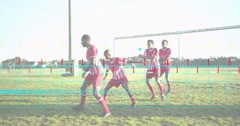 Soccer players forming defensive wall during free kick, red-striped jerseys, teamwork