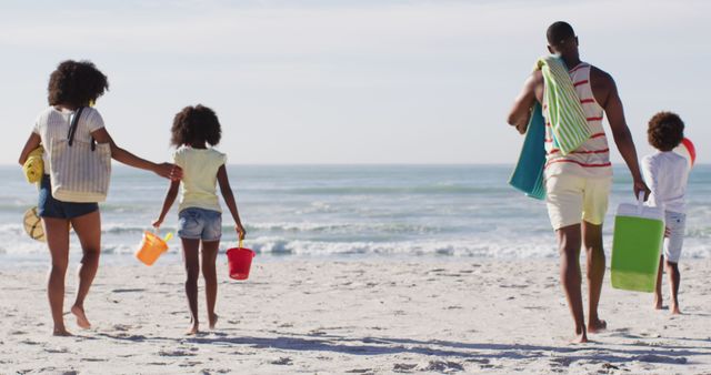 African american parents and their children holding beach equipment on the beach. family outdoor leisure time by the sea.