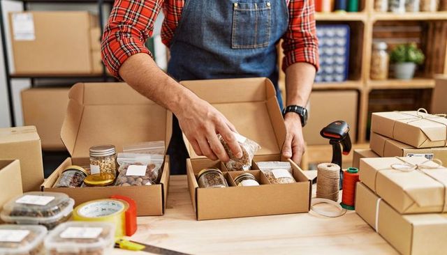 Artisan Small Business Packing: Male Hands Filling Cardboard Boxes with Jars for Fulfillment