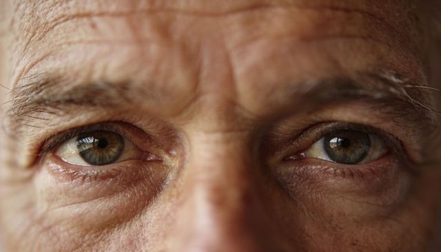 Senior man showing hazel-green eyes and forehead wrinkles in studio close-up