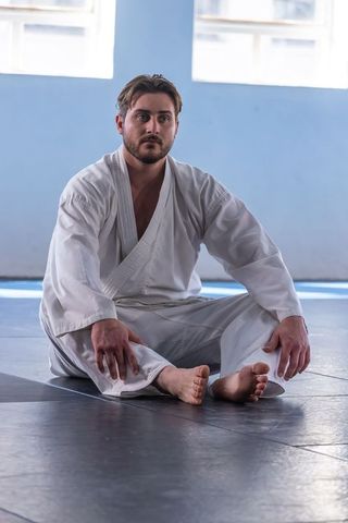 Martial artist meditating in sunlit dojo with calm focus