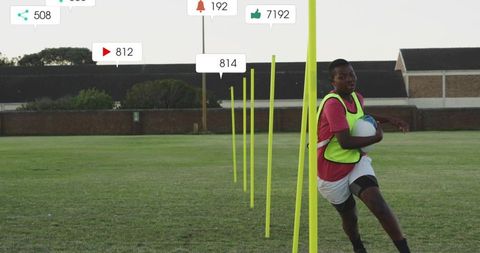 Teen athlete running through agility poles holding rugby ball on grass field training