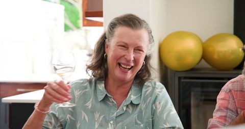 Joyful Senior Woman Enjoying Wine with Friends at a Dinner Party