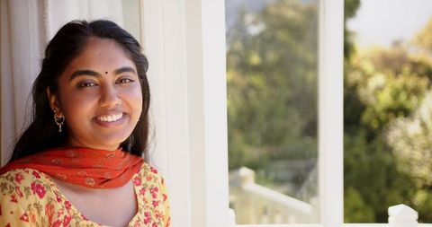 Smiling Indian Woman by Sunlit Window in Traditional Attire