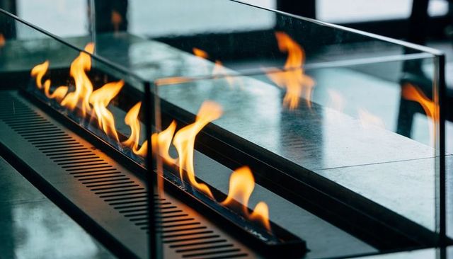 Contemporary linear fireplace with glass guard and flickering flames on stone hearth