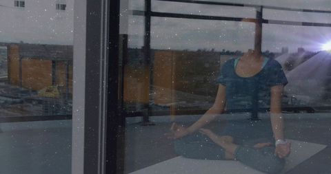 Woman meditating on balcony overlooking city with blurred face