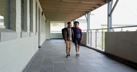 Young diverse friends walking school corridor in sunny daylight