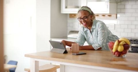 Smiling Senior Woman Using Tablet in Modern Kitchen