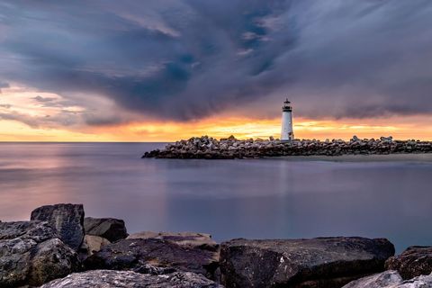 Tranquil Sunset at Seaside Lighthouse with Dramatic Skies