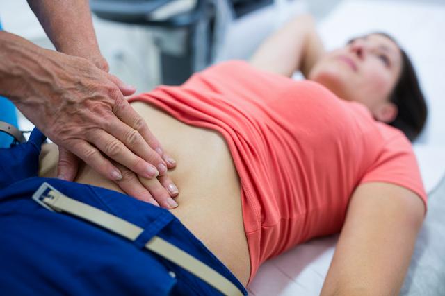 Doctor performing abdominal ultrasound on woman in hospital. Useful for healthcare, medical diagnostics, patient care, and medical procedure concepts. Ideal for illustrating medical examinations, healthcare services, and patient-doctor interactions.