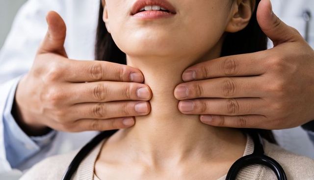 Thyroid examination close-up — clinician palpating neck, doctor hands assessing patient