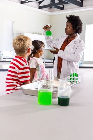 African american teacher demonstrating green chemistry experiment to curious children