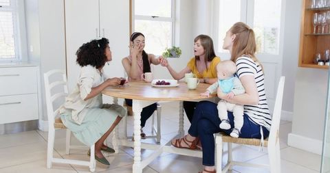 Diverse Group of Friends Celebrating Engagement with Baby at Bright Kitchen Table