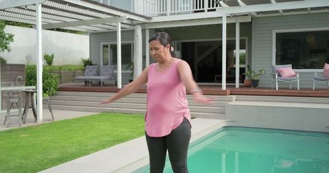 Mature woman practicing balance at backyard poolside for low-impact exercise and wellness
