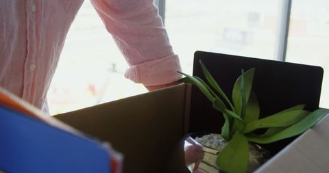 Businessman holding office belongings in cardboard box