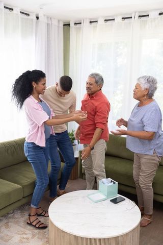 Multigenerational diverse family sharing joyful moment, warm conversation in cozy living room