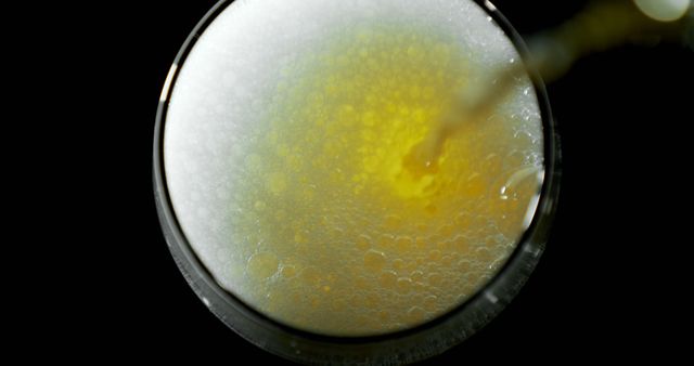 Close-up view of beer pouring into glass, creating bubbles and foam. Can be used for advertising alcoholic beverages, promoting bars and pubs, illustrating freshness and refreshment, or showcasing brewing processes.