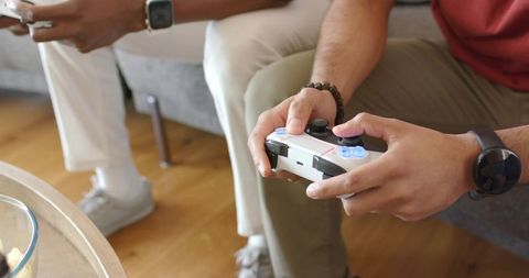 Holding white wireless controller while playing console games in cozy living room