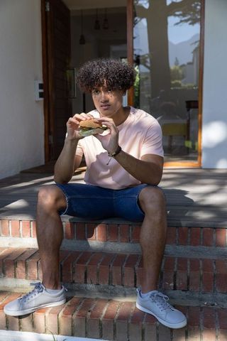 African American Man Enjoying Sandwich on Brick Porch Steps