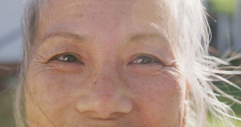 Joyful Senior Asian Woman Outdoors in Sunlight