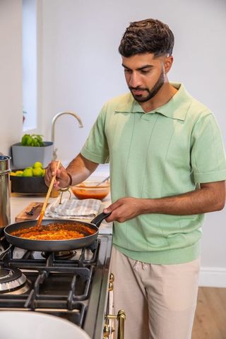 Man cooking tomato sauce in modern home kitchen on stovetop
