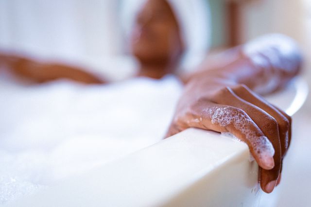 This image captures the essence of relaxation and self-care, featuring an African American woman enjoying a foam bath. Ideal for use in wellness and lifestyle blogs, spa advertisements, self-care promotions, and articles on personal hygiene and relaxation techniques.