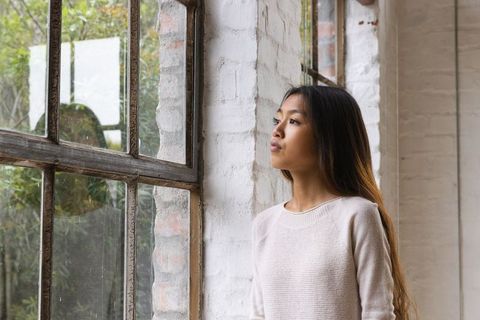Woman Gazing Out Window in Rustic Loft Interior