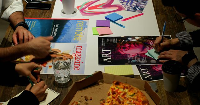 Creative Team Collaborating Over Magazines and Pizza in Office - Download Free Stock Images Pikwizard.com