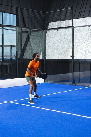 Athletic Man Engaging in Padel Game on Blue Court