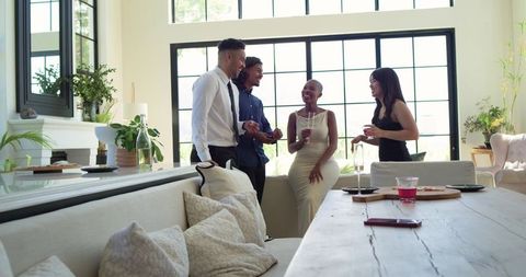 Diverse friends clinking glasses and laughing while chatting at sunlit modern windowsill