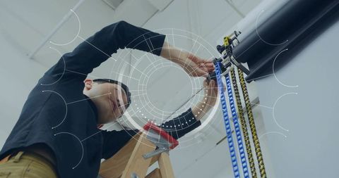 Asian technician adjusting ceiling pulley system on ladder industrial maintenance repair