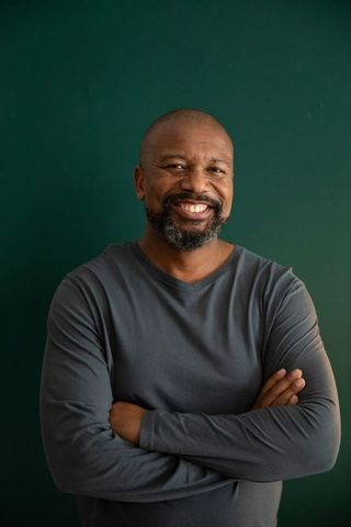 Confident african american man smiling with arms crossed in minimalist studio portrait