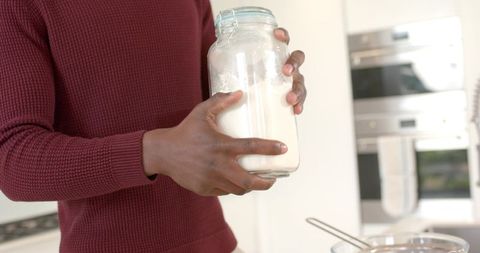 African American Man Holding Jar of Flour in Modern Minimalist Kitchen Preparing to Bake
