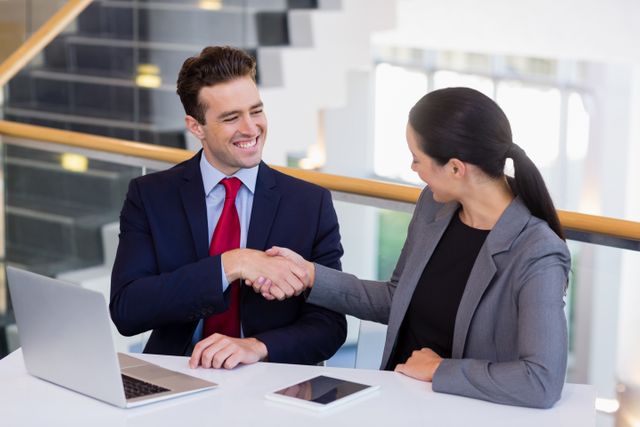 Businessman shaking hands with colleague at desk in conference centre
