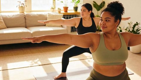 Sunlit Living Room Yoga with Two Diverse Women Practicing Warrior II Pose