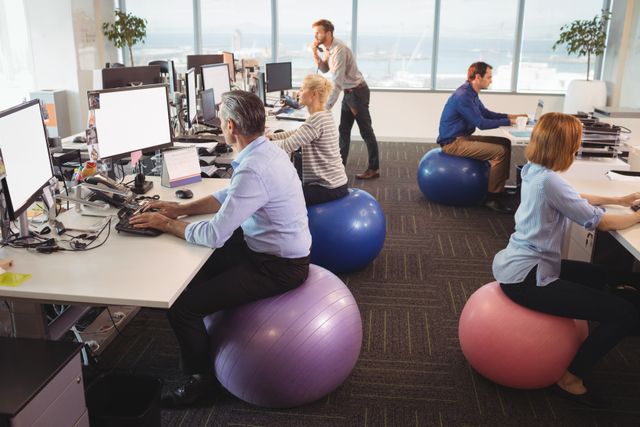 Business people sitting on exercise balls while working at desk in office
