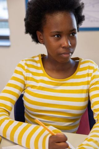 Focused teen student writing during class