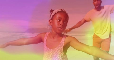 Balancing on beach young girl extending arms while parent plays in colorful sunlight