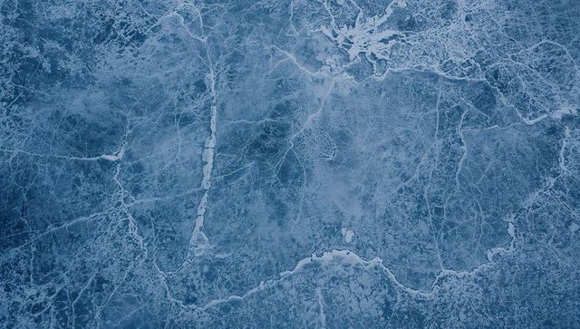 Cracked cerulean ice displaying sinuous fissures, frost ridges and glacial texture