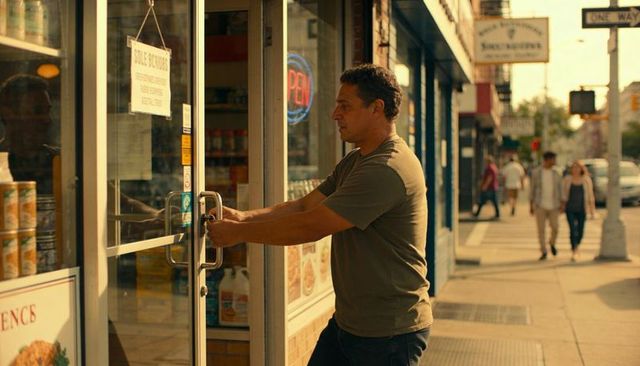 Man opening storefront door at golden hour with neon open sign on urban street