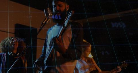 Bearded musician strumming guitar in moody rehearsal space with blue grid overlay
