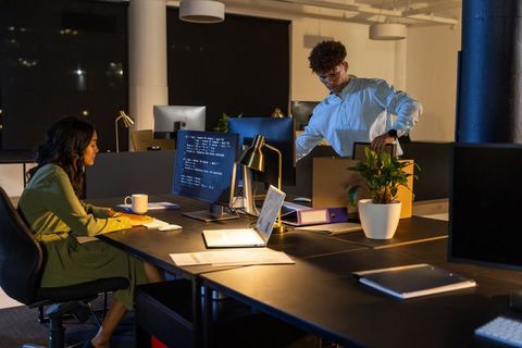 African american coworkers working late in open office with laptop and packing box