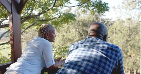 Happy Senior Couple Relaxing on Porch with Wine in the Sun
