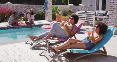 Relaxed Friends Enjoying Refreshing Drinks by Poolside in Summer Sun