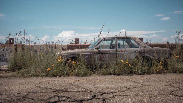 Abandoned Rusty Sedan in Overgrown Urban Lot
