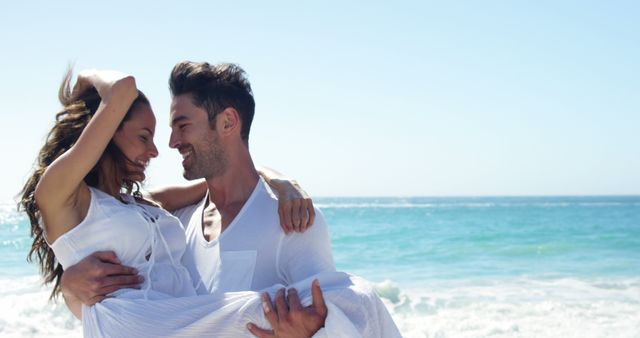Couple enjoying a romantic moment by the ocean on a sunny day, wearing white clothes. Ideal for romance-themed advertisements, travel promotions, wedding invitations, or social media content related to love, relationships, and vacations.