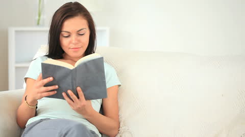 Woman Relaxing with Book on Comfortable Sofa